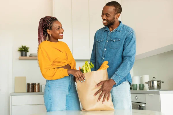 エコバッグ付きの食料品から到着した幸せな黒人配偶者は キッチンインテリア 無料のスペースで梱包を解除します アフリカ系アメリカ人の妻と夫はスーパーマーケットの後に野菜と — ストック写真