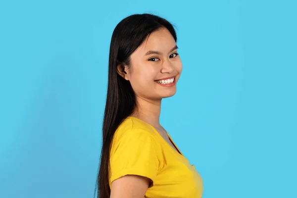 面带微笑自信漂亮的千禧年韩国女学生的画像 身穿黄色T恤 看着相机 隔离在蓝色的背景下 工作室 生活方式 服务和面部表情 — 图库照片