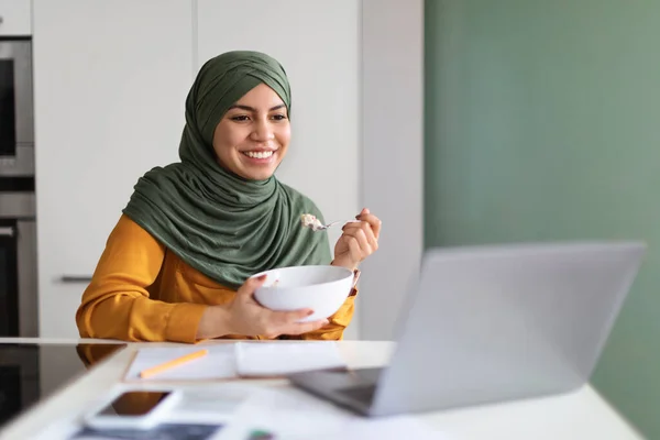 Young Muslim Woman Watching Videos Laptop While Eating Breakfast Kitchen — Stock Fotó