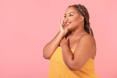 Havluya sarılı duran, doğal güzelliğinin tadını çıkaran, pembe stüdyo arka planında poz veren, özgür bir kadın.