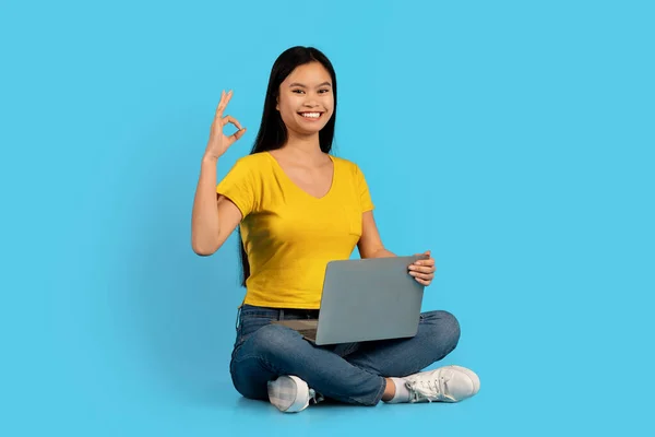 Uśmiechnięty Millenium Koreański Student Siedzieć Podłodze Laptopem Pokazać Znak Ręcznie — Zdjęcie stockowe