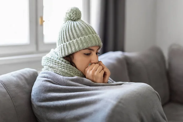 暖房問題 自宅で凍結若い女性のクローズアップショット 毛布に覆われたソファに座って 息で彼女の手を暖める動揺アラブ女性 冷たい屋内を感じ悲しい女性 スペースをコピー — ストック写真