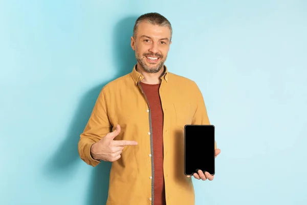 Счастливый Зрелый Мужчина Демонстрирует Цифровой Планшет Указывая Пустой Экран Синем — стоковое фото