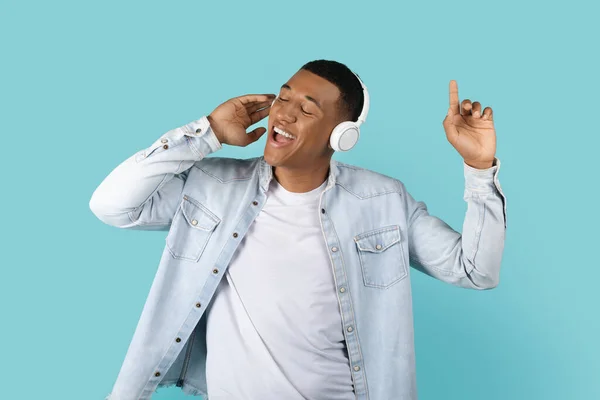 快乐的年轻非洲裔美国男人 穿着休闲和无线耳机 独自歌唱和欣赏音乐 被蓝色背景 工作室 复制空间隔离 有声应用程序的乐趣和空闲时间 休息和放松 — 图库照片