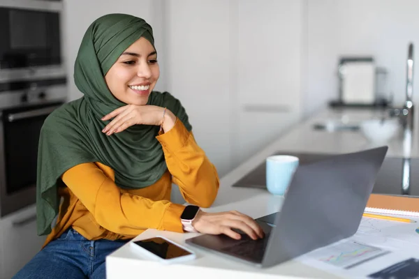 オンラインビジネス 自宅のノートパソコンで働くヒジャブの若いムスリム女性を笑顔に リモートジョブのためのコンピュータを使用して幸せなアラブの女性のフリーランス 仕事の機会を楽しみ スペースをコピー — ストック写真