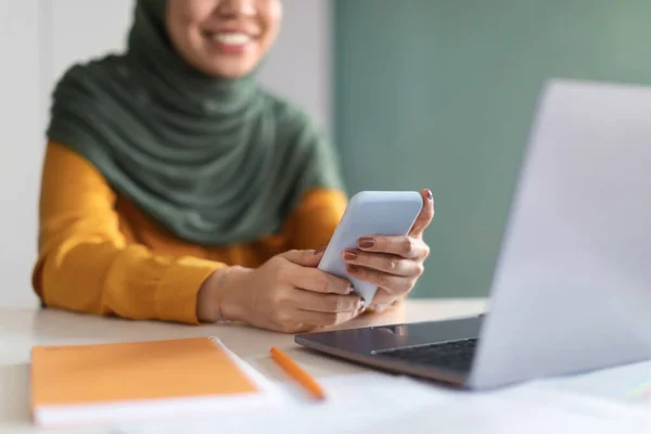 stock image Muslim Woman In Hijab Using Mobile Phone While Sitting At Desk In Office, Unrecognizable Smiling Islamic Lady Shopping Online Or Browsing Modern App For Internet Banking, Closeup With Selective Focus