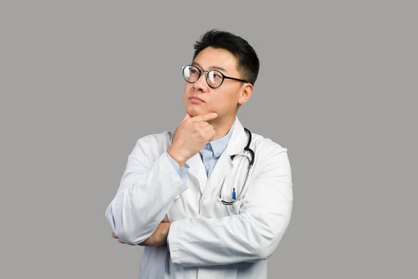 Zamyślony Dojrzały Chiński Facet Terapeuta Białym Płaszczu Okularach Myśli Patrzy — Zdjęcie stockowe