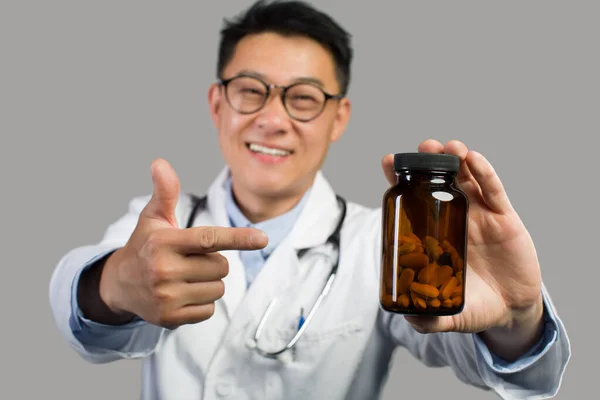 Uśmiechnięty Dorosły Chiński Terapeuta Białym Płaszczu Okularach Wskazuje Palcem Słoik — Zdjęcie stockowe
