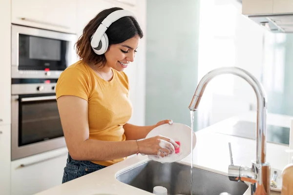 Νεαρή Άραβα Γυναίκα Φορώντας Ασύρματα Ακουστικά Που Πλένουν Πιάτα Στην — Φωτογραφία Αρχείου