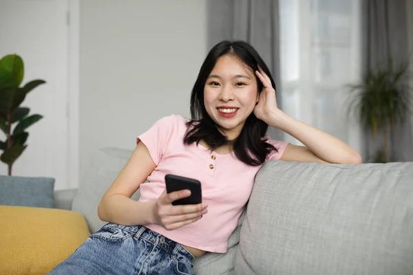 人々と技術の概念 スマートフォンを使って幸せなアジアの女性の肖像画 ソファに座って カメラを見て笑顔 韓国語の女性オンラインチャット — ストック写真