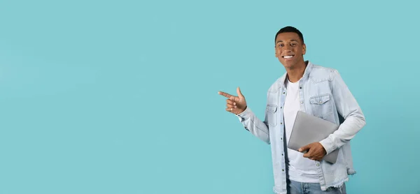 Улыбающийся Уверенный Молодой Африканский Американец Ноутбуком Указывает Пальцем Пространство Копирования — стоковое фото