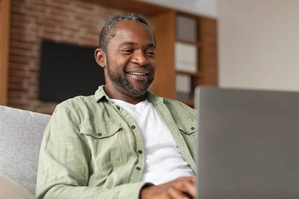 Neşeli Olgun Siyahi Bir Adam Bilgisayarda Yazı Yazıyor Video Görüşmesi — Stok fotoğraf