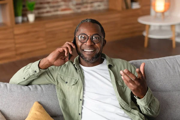 幸せな幸せな幸せな成熟した黒の男性のメガネの呼び出しで スマートフォン リビングルームのインテリア コピースペースで余暇に良いニュースを持っています 家でのゴシップ コミュニケーション 人間の感情やライフスタイル — ストック写真