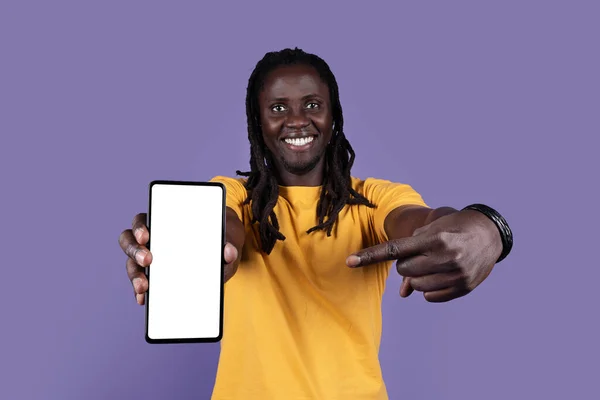 陽気なクールな黒の男とともに花嫁で黄色のTシャツ指す真新しい携帯電話上の白いブランクスクリーン以上の紫のスタジオの背景 お勧めします素敵なモバイルアプリやオファー モックアップ — ストック写真