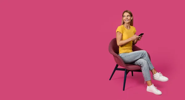 Sandalyeye Oturmuş Akıllı Telefondan Sohbet Eden Pembe Arka Planda Stüdyoda — Stok fotoğraf