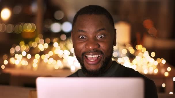 素晴らしいニュースだ 若い興奮したアフリカ系アメリカ人男性の肖像画を閉じます電子タブレットで電子メールを読んで 広く笑顔 夜に自宅で達成を楽しんで スローモーション — ストック動画