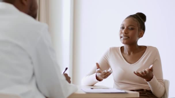 若い心配アフリカ系アメリカ人の女性がオフィスで医者と話をして症状を言い彼女の健康状態について不満を言い — ストック動画