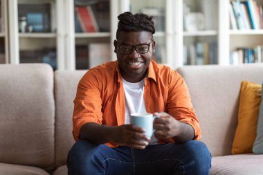 Oturma odasındaki koltukta oturan, sabahları taze kahvenin tadını çıkaran kameraya gülümseyen, fotokopi çeken binlerce yıllık havalı Afro-Amerikan erkeği. Yurtiçi yaşam tarzı kavramı