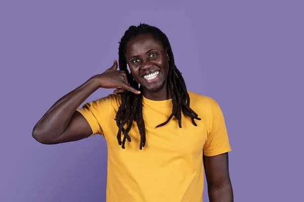だから私に電話して 紫色の背景に隔離されて立っている間 黄色のコールサインと笑顔を示すハンサムな長髪のアフリカ系アメリカ人の若者 スタジオショット 広告のためのコピースペース — ストック写真