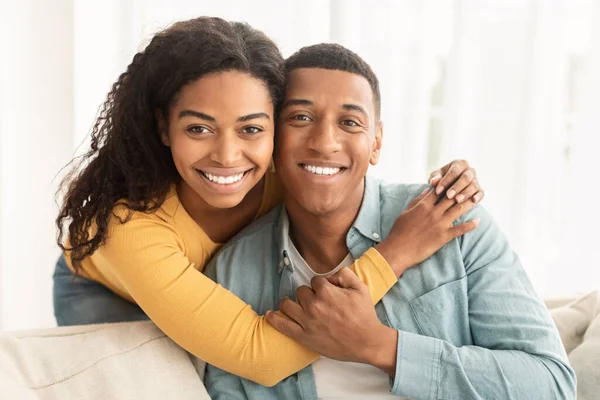 幸せな若いアフリカ系アメリカ人の妻のソファの上に夫を抱き込み リビングルームのインテリアでカメラを見て スペースをコピーします ビデオ通話 関係と自宅で無料で一緒にリラックス — ストック写真