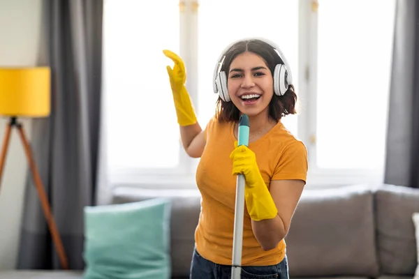 Alegre Mujer Árabe Auriculares Inalámbricos Cantando Mientras Hace Limpieza Casa —  Fotos de Stock