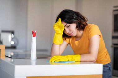 Genç Arap Kadın, evde mutfağı temizlerken yorgun hissediyor, Ortadoğu kadın eldivenleri giyip, masa yıkadıktan sonra yorulmuş, kırılıyor ve alnını siliyor.