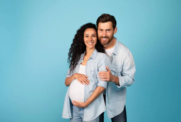 Usmívající Mladý Evropan Objímající Těhotnou Ženu Ležérně Velkým Břichem Izolovaný — Stock fotografie