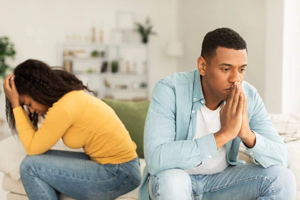 Sad offended millennial african american wife and husband ignore each other after quarrel, think about breakup in room interior. Emotions, problems with family relationship, stress and crisis at home