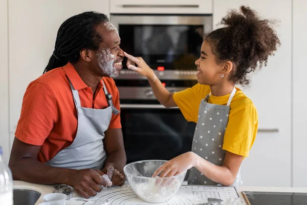 Cheerful Black Dad And Daughter Playing With Floor While Baking Together In Kitchen, Happy African American Father And Preteen Female Child Having Fun And Enjoying Cooking At Home, Closeup