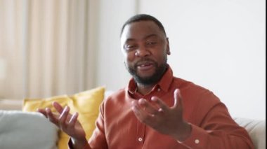 Mutlu yaşam tarzı koçluğu. Mutlu Afro-Amerikan Psikoterapist Adam 'ın kamera görüntüsü. Motivasyon videosu kaydediyor, evde oturuyor, yavaş çekim, boş alan.