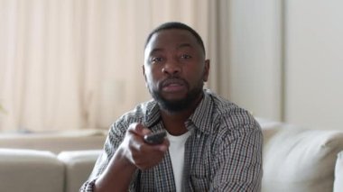 Duyarsızlık ve kayıtsızlık. Sıkıcı Afro-Amerikan bağırsağının TV 'de kanal değiştirdiği, hafta sonu evde yalnız dinlendiği, yavaş çekim, boş alan.