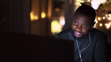 Yabancı ortaklarla çalış. Genç, Afro-Amerikan erkek müdürünün internetten partnerlerle görüntülü konuşması, projeyi tartışması, evden geç saatlere kadar çalışması, çekim takibi, yavaş çekim, serbest alan.