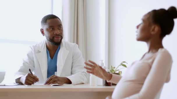 妊娠中の医療 若い妊娠中のアフリカ系アメリカ人の女性は 医師の任命に座って 健康状態について話します 彼女のビタミンの処方を与えます 撮影を追跡 スローモーション — ストック動画