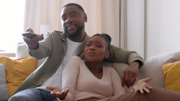 婚姻周末快乐 年轻的非洲裔美国配偶一起在家里看电视 讨论节目的选择 跟踪镜头 慢动作 自由空间 — 图库视频影像