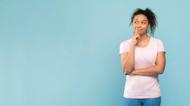 Düşünceli afro-amerikalı kadın boş alana bakıyor ve düşünüyor, mavi stüdyo arka planında duruyor, panorama. Bir düşüneyim.