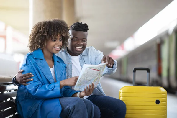 快乐的黑人夫妇坐在火车站时可以在地图上查看旅行路线 快乐的年轻非洲裔美国人在一起等火车时可以计划旅行 复制空间 — 图库照片
