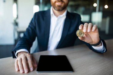İş adamı masada Bitcoin para gösteriyor. Tabletle birlikte ofis içi boş ekran, kırpılmış, model. İş ve kripto para birimi uygulaması, harika bir teklif ve reklam, gelecekteki para