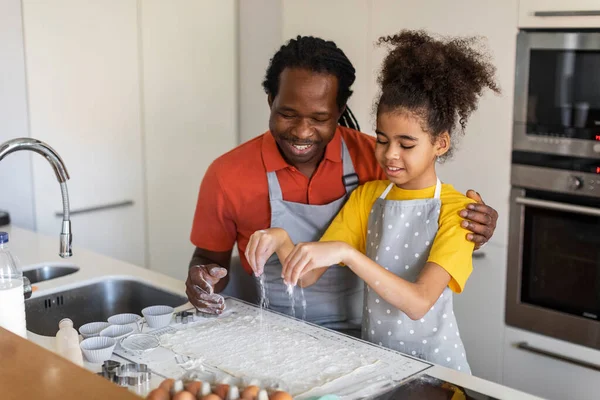 Loving Black Dad And Daughter Preparing Dough For Muffins And Having Fun In Kitchen, Happy African American Daughter Baking With His Preteen Female Child At Home, Enjoying Cooking Pastry