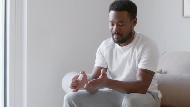 流行后的习惯 年轻的非洲裔美国人在手上喷洒清洁剂 在家里内部消毒手掌 跟踪射击 慢动作 空旷的空间 — 图库视频影像
