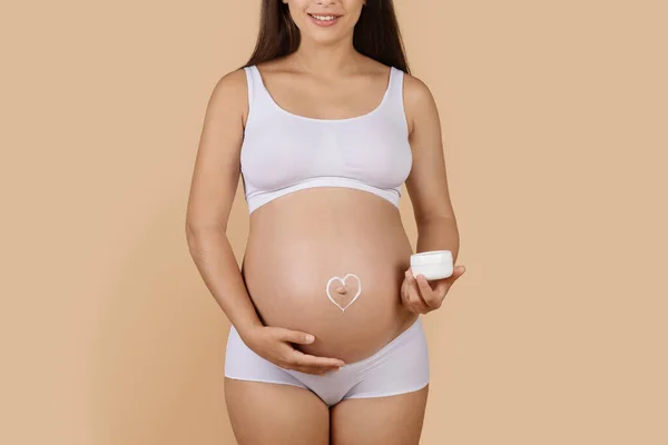 Pregnant Woman Heart Made Cream Painted Her Belly Standing Beige — Fotografia de Stock