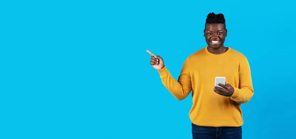 Young Black Man Holding Smartphone Pointing Aside Copy Space Finger — Foto de Stock
