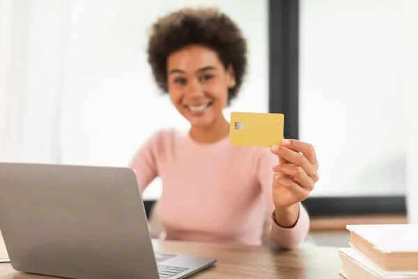 Glad young mixed race woman manager show credit card use laptop, checks finances on bank account, recommend saving in office interior, blurred. Work, business remotely, online shopping, huge sale