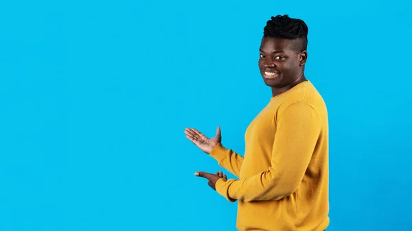 Handsome Young Black Man Pointing At Copy Space With Two Hands, Happy African American Male Demonstrating Free Place For Design Or Advertisement While Standing Isolated Over Blue Background, Panorama