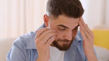 Personal problems and despair. Close up portrait of young depressed middle eastern man feeling stress, rubbing his nose bridge, working at home, tracking shot, slow motion