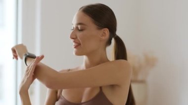 Body stretching before workout. Close up portrait of young happy beautiful woman warming up her muscles, twisting her wrist at home and smiling, slow motion, free space