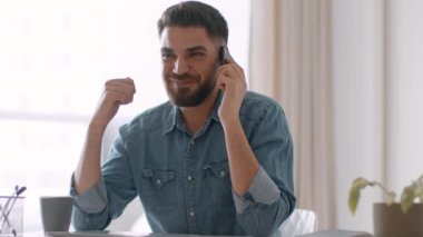 Business negotiations. Young happy arab guy discussing project with partners on cellphone, working from office, enjoying partnership, tracking shot, slow motion, empty space