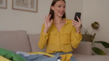 Young happy woman video chatting with friend via smartphone, showing passport and tickets to friend, anticipating her future vacation trip, tracking shot, slow motion, free space