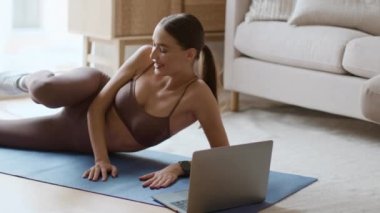 Exhausting online training. Young lazy woman training at home, watching video tutorial on laptop and turning it off, feeling tired and annoyed, slow motion, free space