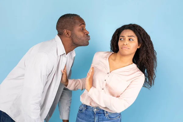 友爱区的概念厌恶的黑人年轻女人避免中年男人不想要的亲吻 中年男人试图接近她 拉起她的嘴唇 女士用手掌拒绝并表现出停止动作 — 图库照片