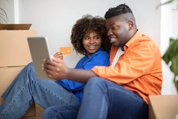 Online Shopping. Black Smiling Couple Using Digital Tablet And Credit Card While Purchasing In Internet, Happy African American Spouses Ordering Furniture After Moving To New Home, Closeup Shot